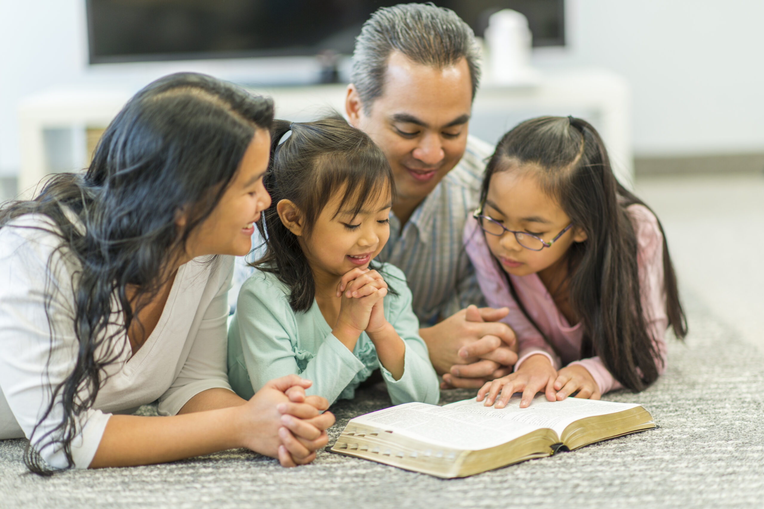 Family reading the Bible together in their living room.